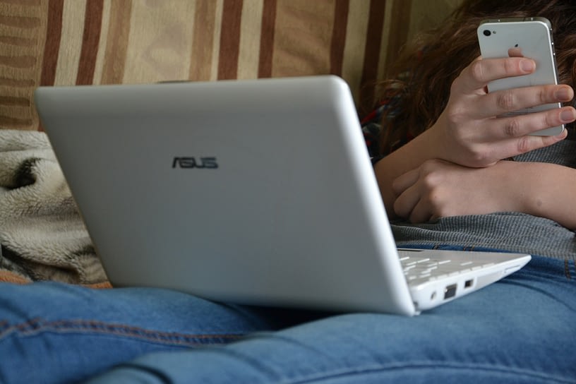 person using laptop computer and smart phone that have accessibility features for the blind